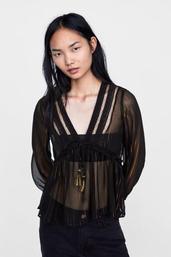 Blusa fluida semitransparente de escote pico con encaje y manga larga, con detalle de hilo metalizado y corte en cintura con lazo (Zara, 25,95 euros).