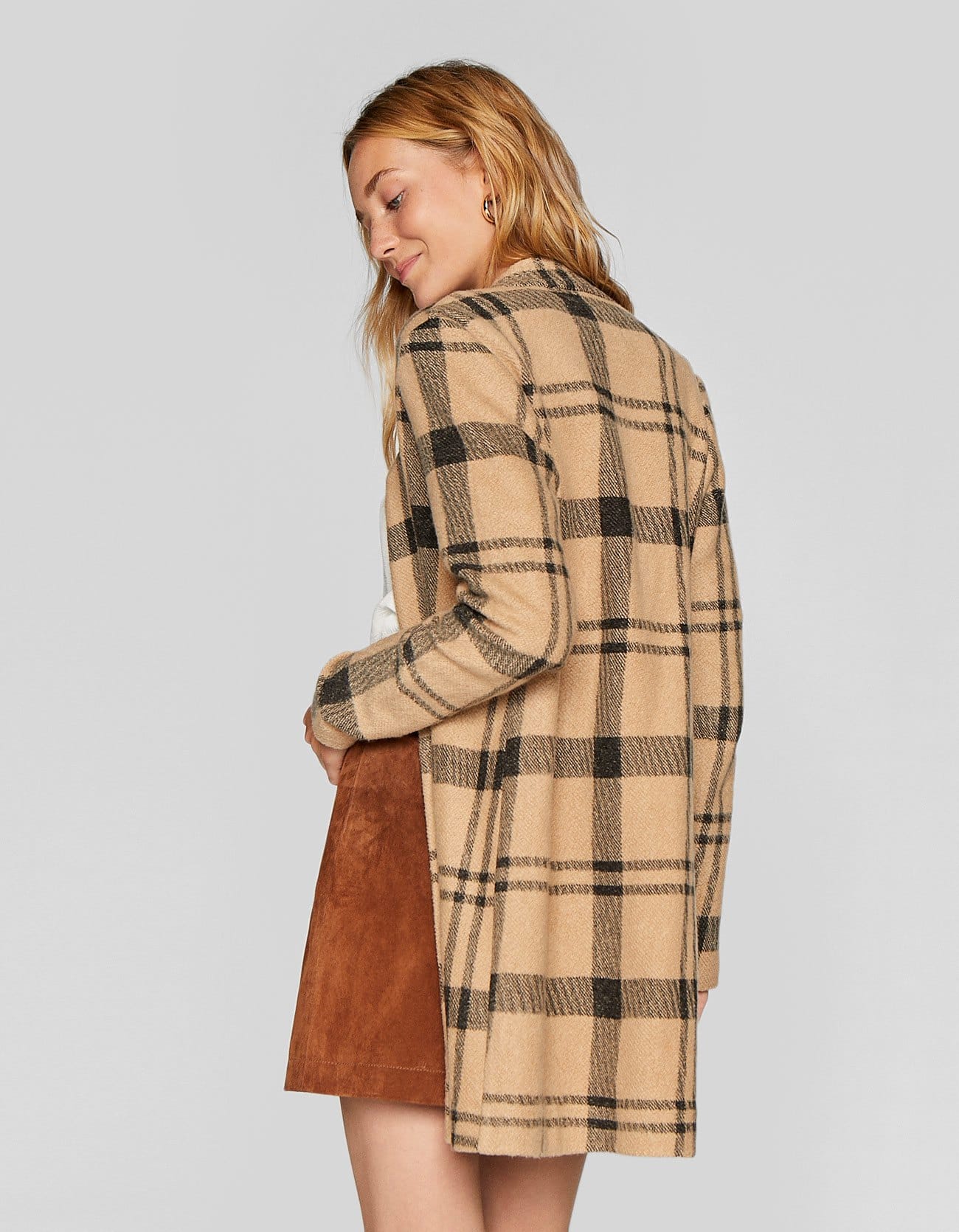 Para el entretiempo nos quedamos con este abrigo cámel con estampado tartán, que en las rebajas de Stradivarius pasa de 29.99 a 19.99 euros.