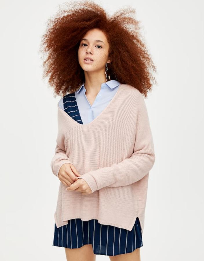 Atención a este pichi de tirantes que asoma bajo el jersey de punto suave y escote de pico color rosa (19,99 euros). Las rayas blancas sobre azul marino son directamente espectaculares.