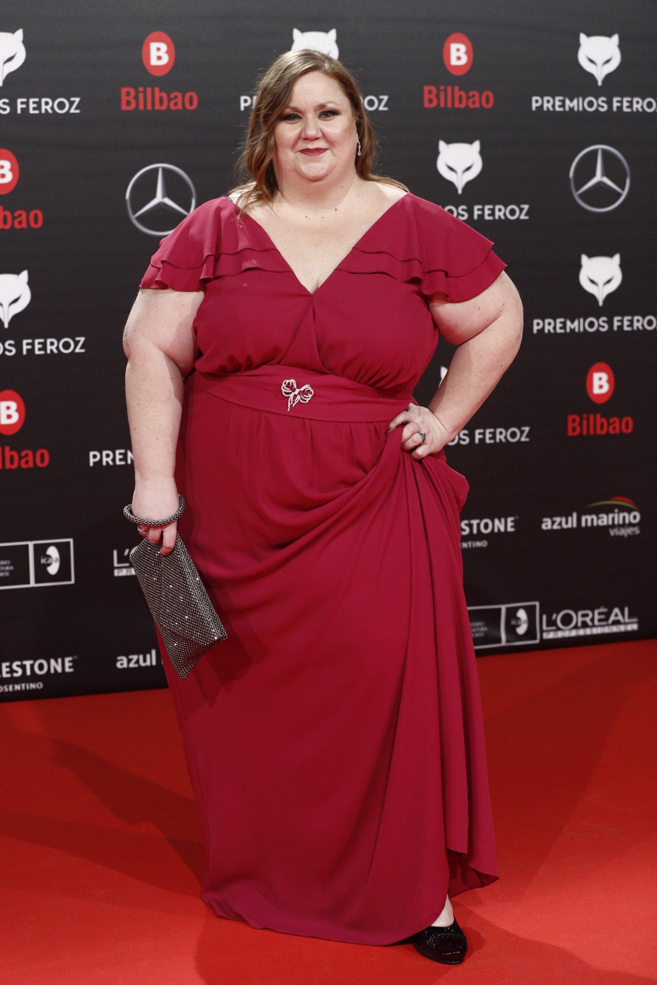 La actriz de 'Vis a Vis' acude como invitada a los Premios Feroz. Ha participado en la película 'Campeones', que opta a cuatro candidaturas. Para la ocasión ha escogido un diseño largo en color burdeos con escote y detalle de volantes en las mangas.