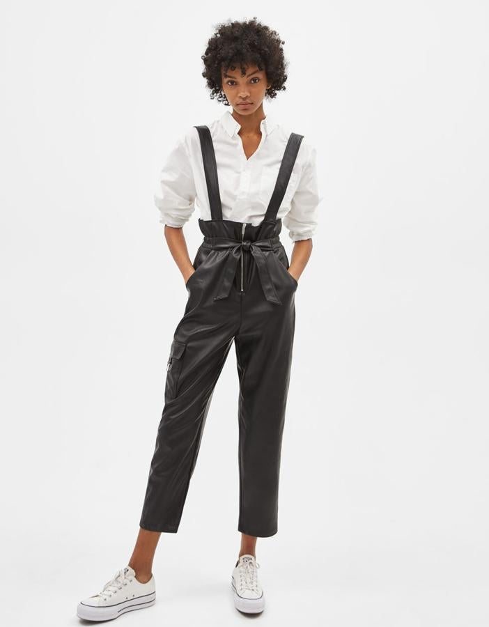 Peto efecto piel con tirantes ajustables, dos bolsillos delanteros, un bolsillo en pernera con anilla y cintura elástica. Lleva cierre delantero con cremallera metálica y cinturón (29,99 euros).