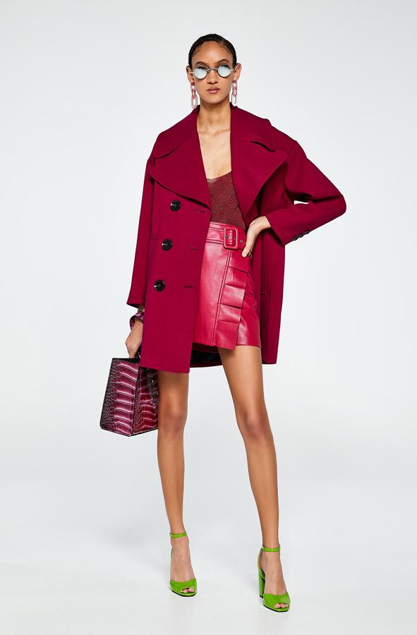 Abrigo de solapa grande (59,99 euros), conjuntado con una falda de efecto piel (25,99 euros) y con un top (15,99 euros).