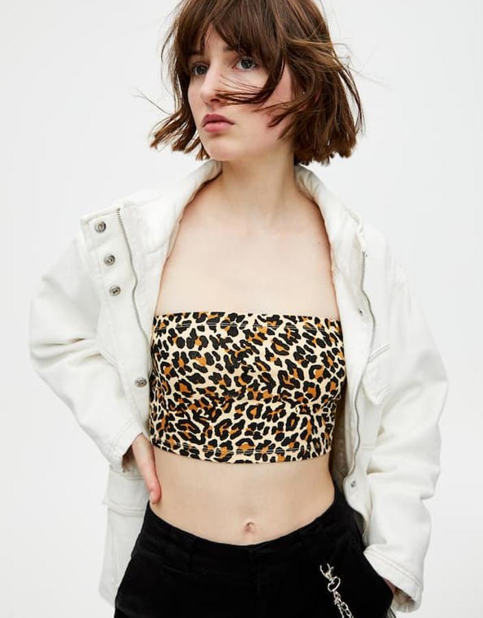 Top 'bandea'u en 'estampados 'de leopardo, en tejido elástico (3,99 euros) bajo una chaqueta vaquera con cuatro bolsillos delanteros, frunces, costuras en contraste, manga larga, cierre de cremallera y cuello alto (49,99 euros). También pantalón cargo tipo chino en tejido de sarga con cadena en un bolsillo, cierre de cremallera y bajo elástico (22,99 euros).