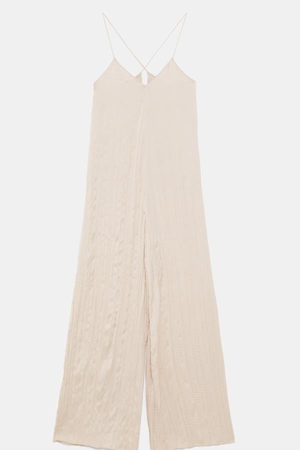 Mono fluido de color crema con escote en pico y tirantes cruzados. Es de  Zara  y puedes hacerte con él por  29,99 euros .