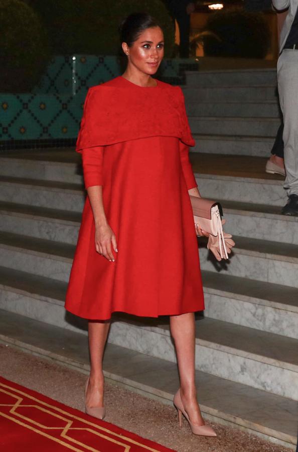 Para su llegada a Marruecos Meghan Markle apostó por un elegantísimo vestido rojo de Valentino con detalle de capelina. Los complementos también los firmaba la casa italiana.