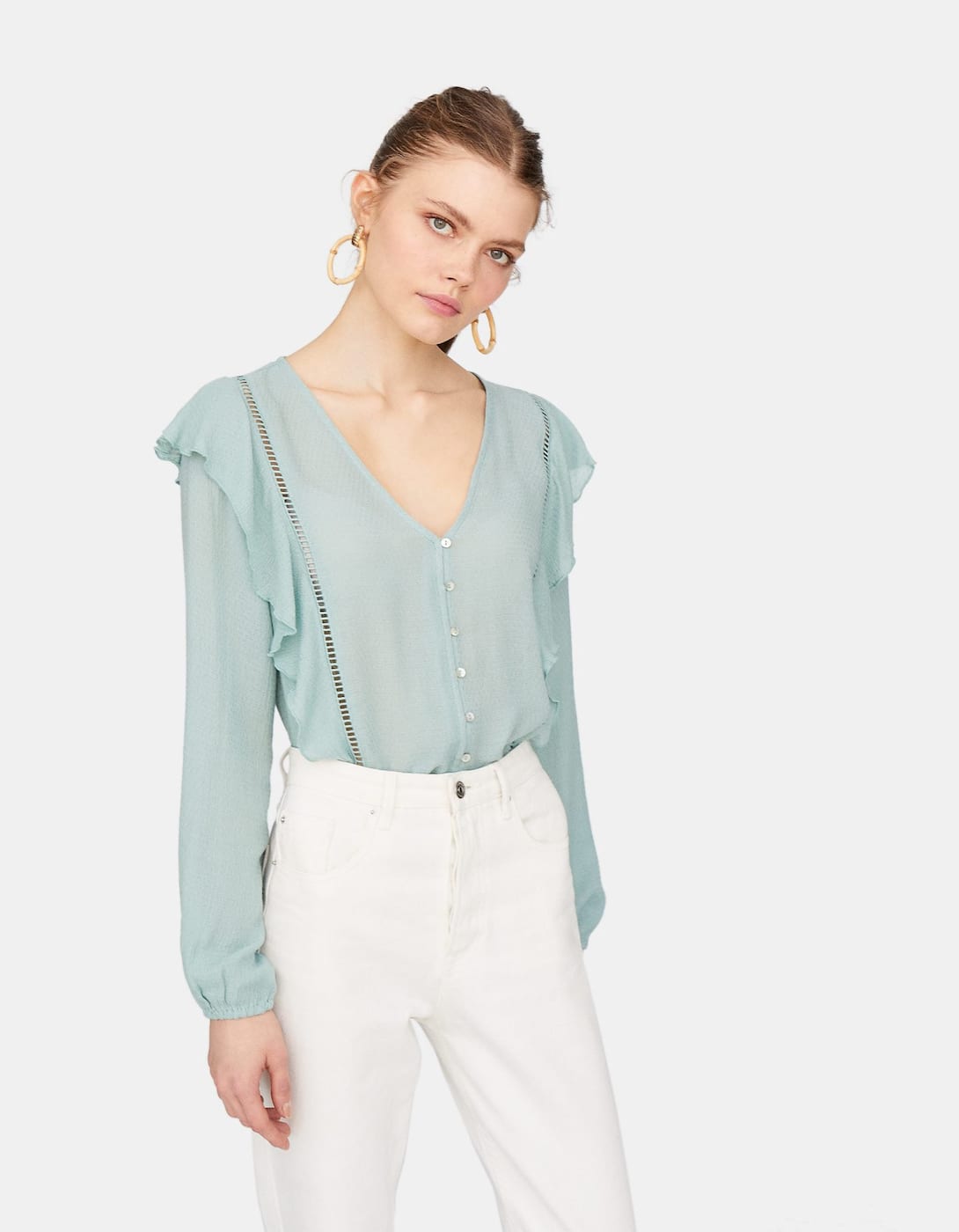 Una blusa verde agua tradicional con un escote bonito pero mucho más original gracias a los volantes que la decoran. De Stradivarius. (17,99 euros).