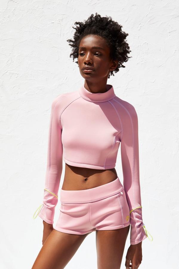 Precioso conjunto de top y shorts con detalles en verde flúor. El top 'cropped' lleva el cuello subido y la manga larga adornada con un cordón ajustable (25,95 euros). El short es elástico y de tiro alto, también con un detalle (un pequeño corazón) en verde flúor (19,95 euros).