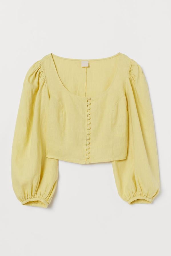 Blusa corta en tejido de lino. El diseño es de corte recto con escote amplio, botones revestidos delante y mangas globo largas (39,99 euros).
