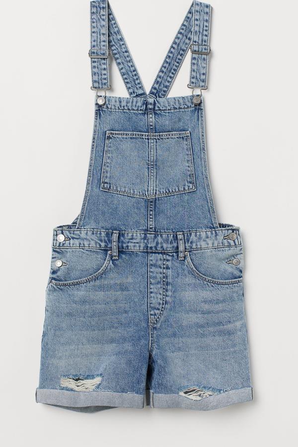 Peto corto en denim lavado con detalles desgastados, dobladillo cosido vuelto en las perneras y bajos deshilachados sin rematar. (H&M, 24,99 euros).