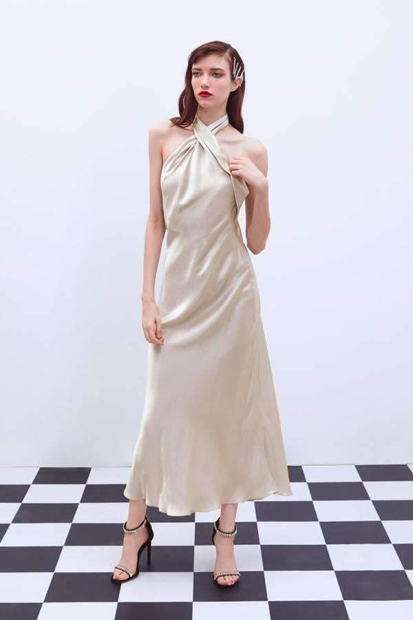 De raso y escote halter, lleva la espalda al aire. En color champagne, te quedará de 10 con unos labios rojos (59,95 euros).