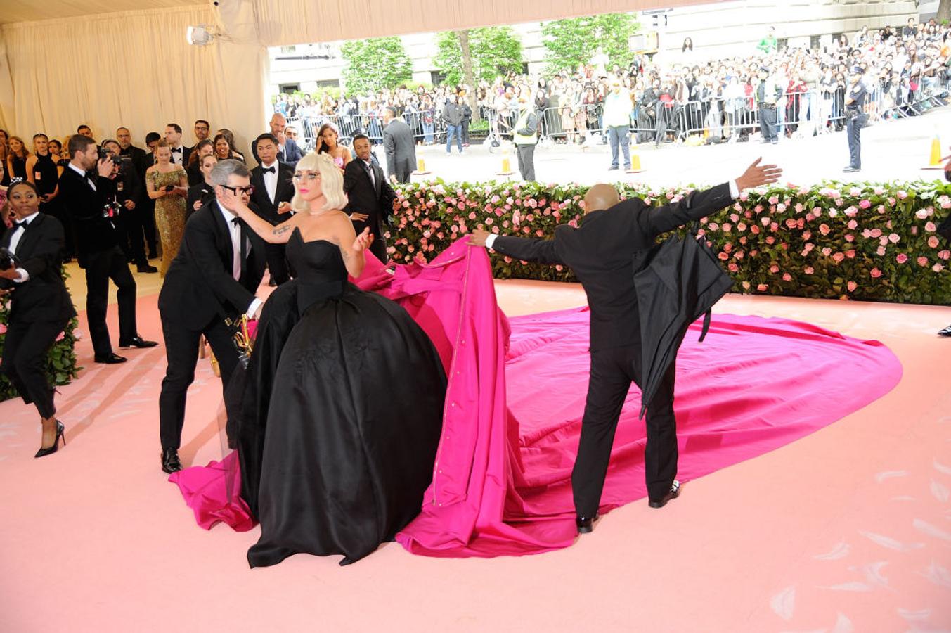 Pero con Lady Gaga nada es lo que parece, y la sorpresa llegaba cuando sus asistentes le despojaban del abrigo-vestido-capa para dar paso a un imponente vestido negro con escote palabra de honor, cuerpo corsé y falda con gran volumen, un diseño que no deja de recordarnos a  su look de los Oscar de 2019 .