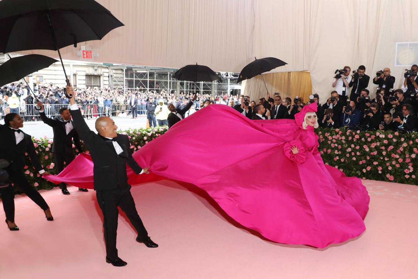 Lady Gaga llegó como la diva que es, escoltada por un séquito de asistentes en esmoquin que portaban paraguas y que hacían que su maxi abrigo vestido de seda fucsia de Brandon Maxwell cobrara vida...