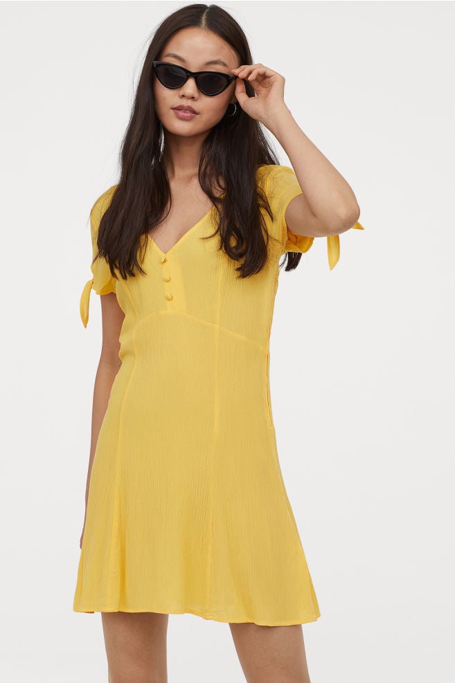 ¿Y si cambiamos el corte midi por el mini? El low cost tiene prendas tan cool como este vestido amarillo de H&M con escote a pico y lazada en las mangas. (24,99 euros).