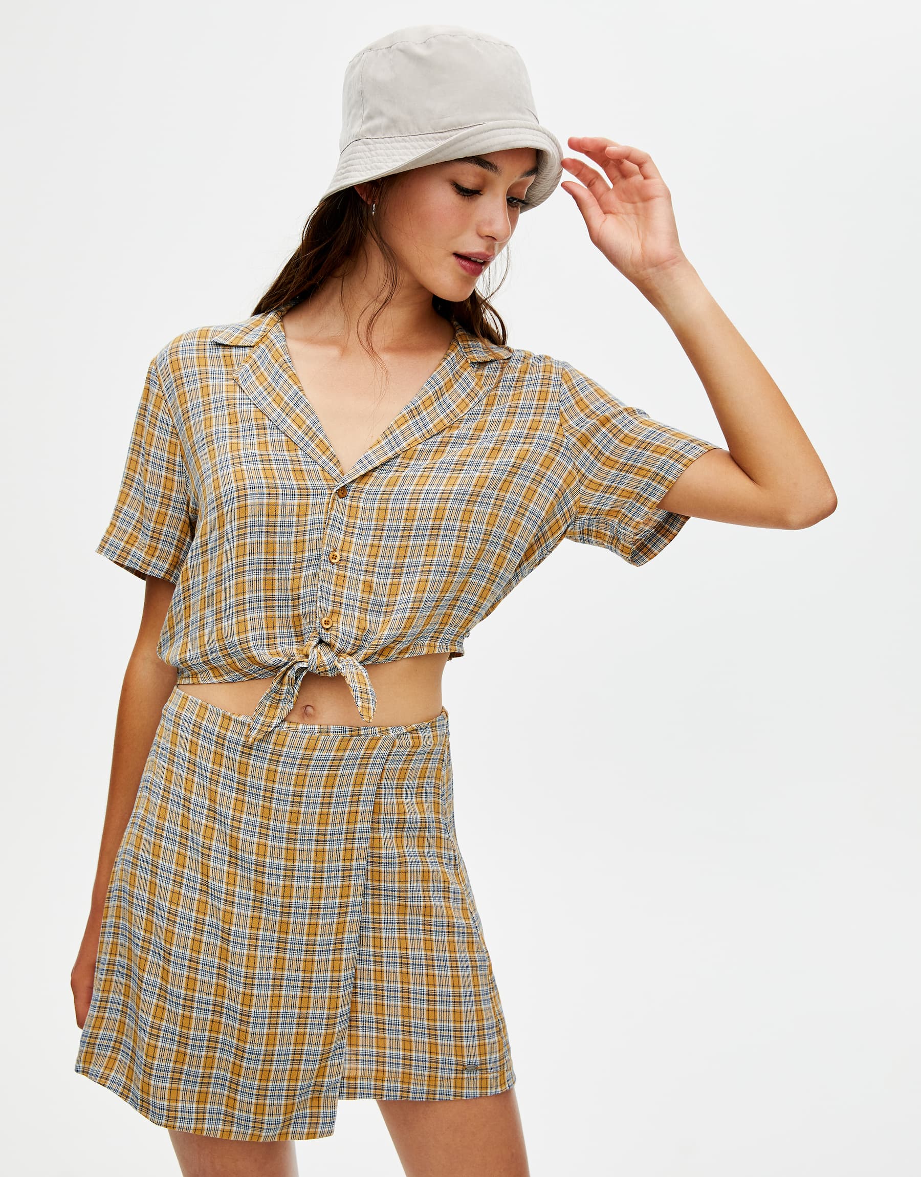 Falda pareo con estampado de cuadros y camisa abotonada con nudo a juego: 15,99 euros la falda y 17,99 euros la camisa. En Pull & Bear.
