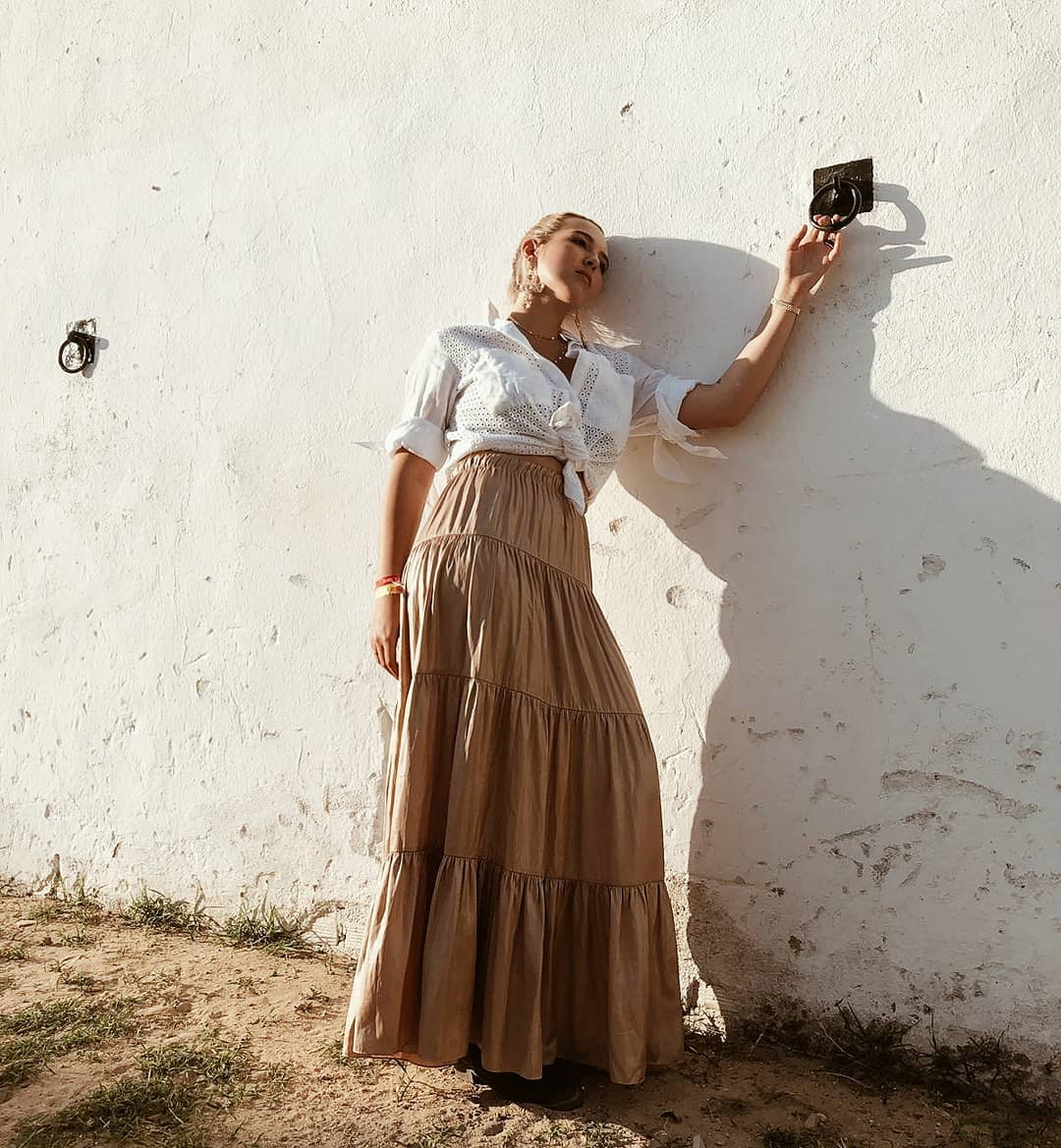 Ser rociera es una actitud, y Alba Díaz la tiene, y lució  perfecta  con este conjunto de falda color arena metalizada de  Zara (49.95 euros)  y blusa blanca calada anudada a la cintura.