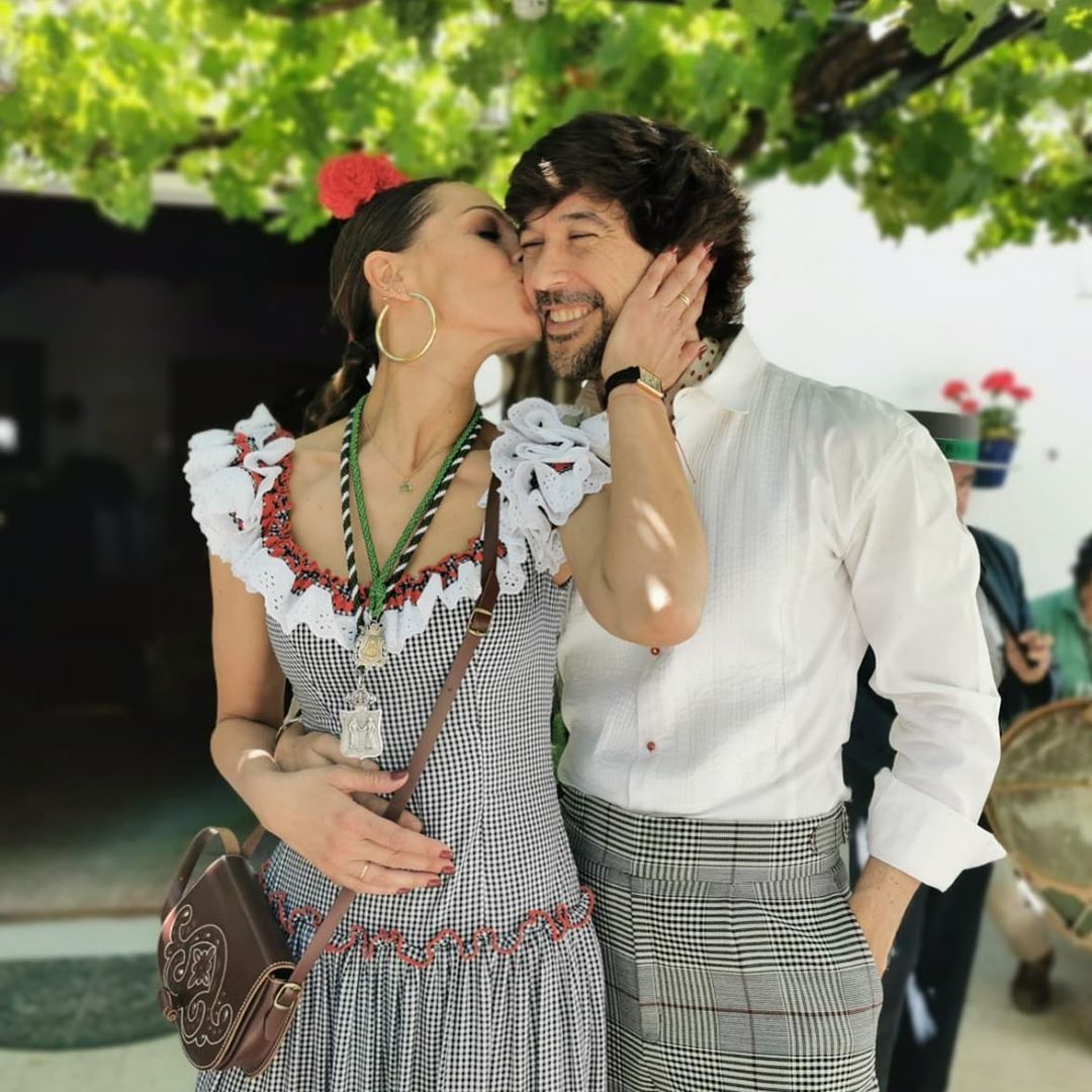 En este look Eva González apuesta por un traje de flamenca más tradicional, con estampado de vicky en negro y blanco y detalle de volantes en mangas y escote firmado por Pilar Vera.