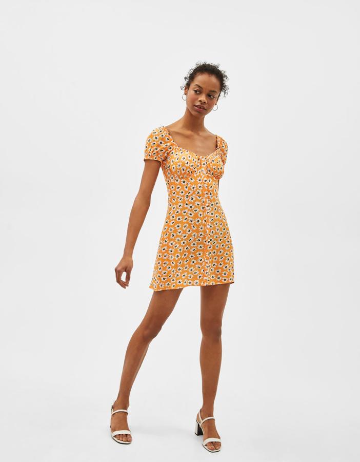 Mini vestido naranja con estampado floral y escote mesonero. Su precio con descuento pasa de 19.99 a 13.99 euros antes de las rebajas de verano de Bershka.