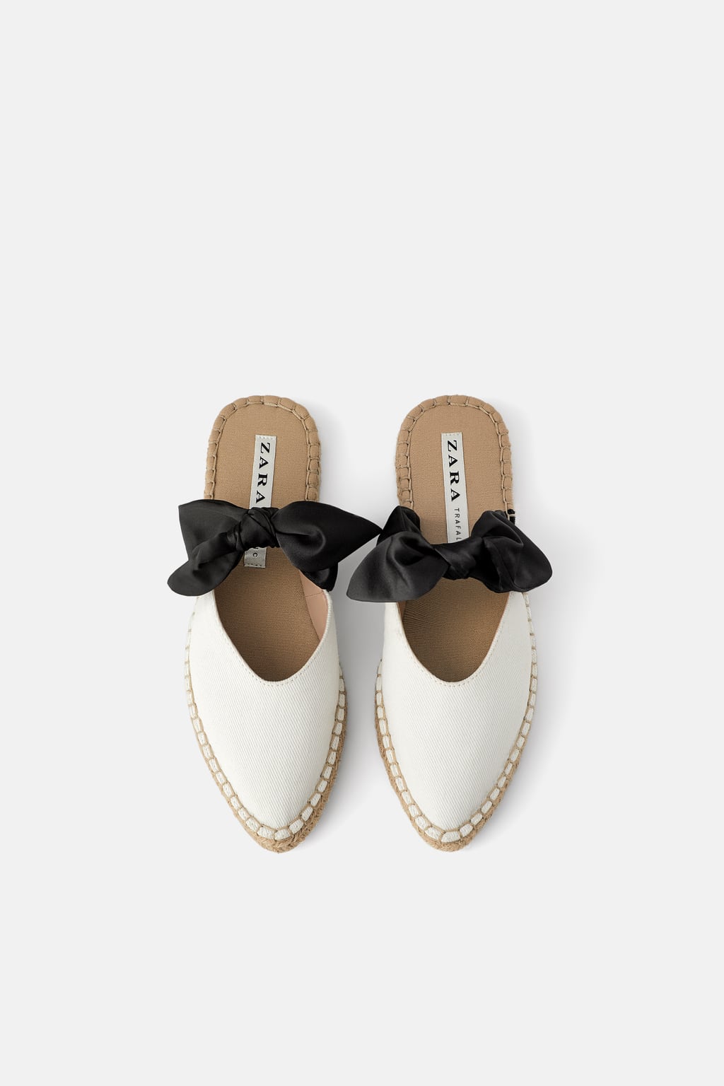 Mule natural en tono blanco con detalle de lazo negro. Suelas de esparto. De Zara. (22,95 euros).