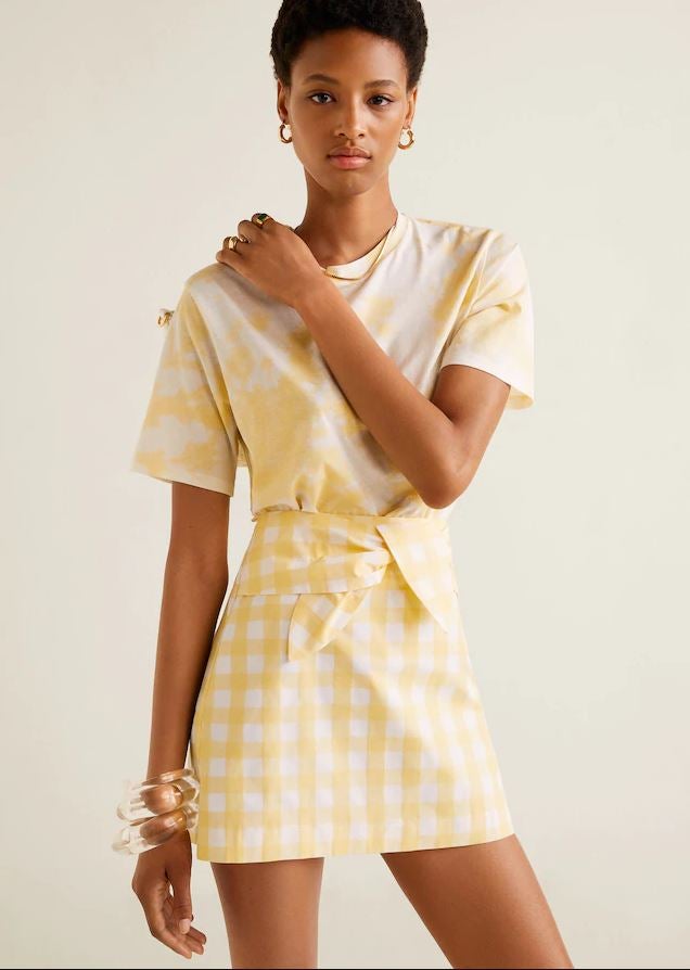 Esta mini falda con estampado de cuadros de Vichy en color amarillo y blanco de Mango pasa de 22.99 a 15.99 euros en las rebajas.
