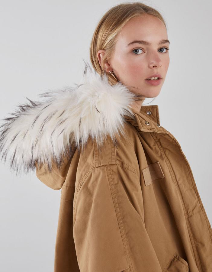 Cazadora corta con interior forrado con tejido efecto pelo, bolsillos laterales, cierre de cremallera, cintura ajustable y pelo en capucha extraíble (Bershka, 24,99 euros)