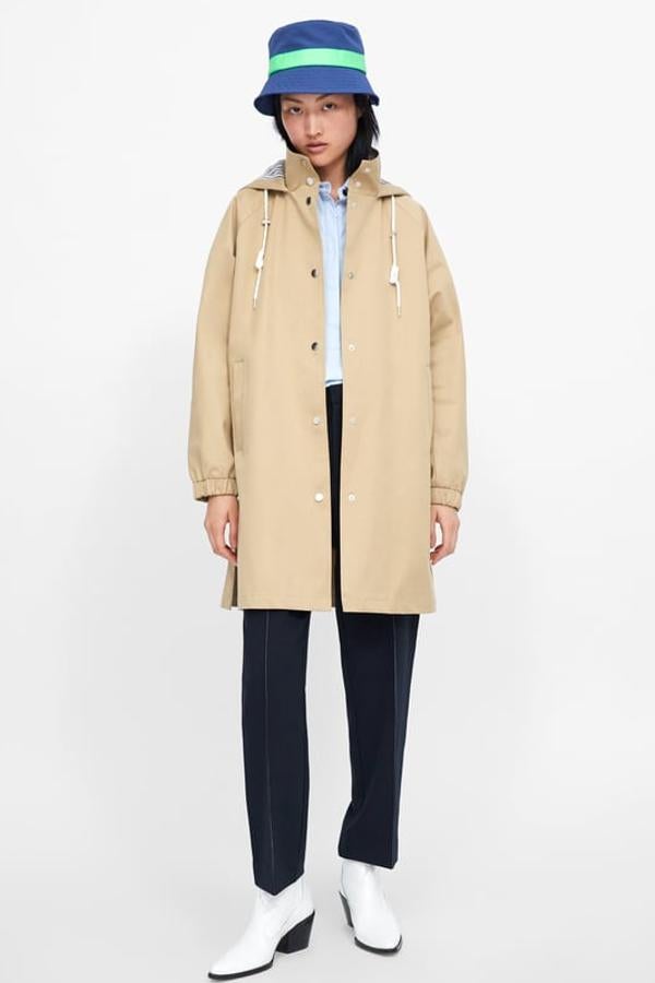 Parka color camel con el cuello subido y capucha ajustable. Lleva manga larga acabada en puño elástico, bolsillos delanteros de vivo,bajo con aberturas laterales y cierre frontal con botón presión (Zara, 25,99 euros).