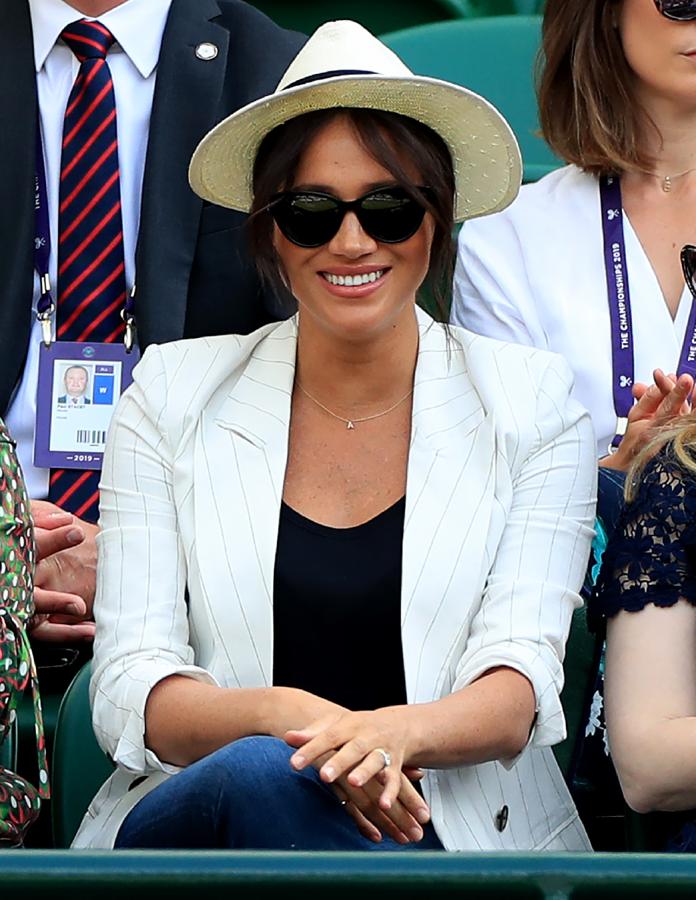 Para animar a su amiga Serena Williams en el Torneo de Wimbledon Meghan Markle ha apostado por un look muy sencillo con blazer de verano, vaqueros de Ralph Lauren y sombrero Panamá que, además, tenía  un detalle muy tierno para 'baby Sussex' : un colgante de oro con la inicial A de Archie.