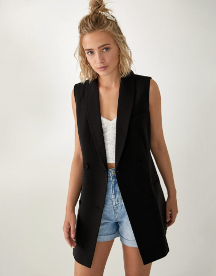 Short en denim azul claro con ajuste mom y el bajo con vuelta (17,99 euros), top bralette de blonda (12,99 euros) y chaleco negro oversize y liso (29,99 euros).