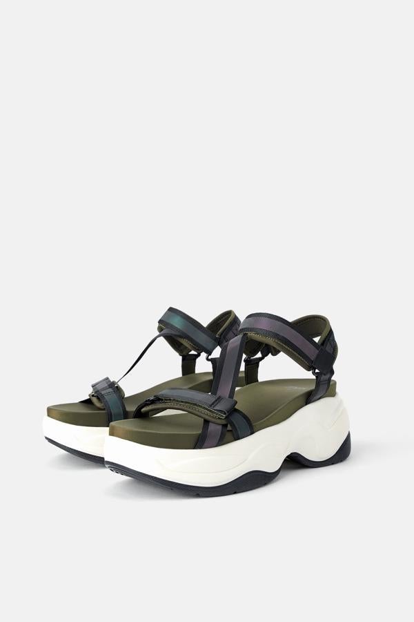 Sandalia plana en combinación de colores, con tiras de distintos materiales y con detalle iridiscente. La suela lleva volumen en relieve en una combinación de colores. Cierra mediante cinta adherente en pulsera al tobillo (Zara, 39,95 euros).