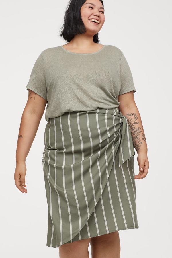 Falda de tela con talle alto, frente cruzado cosido con drapeado, cinturón de anudar ancho y cremallera oculta en un lateral. Va sin forrar (H&M, 10,99 euros).