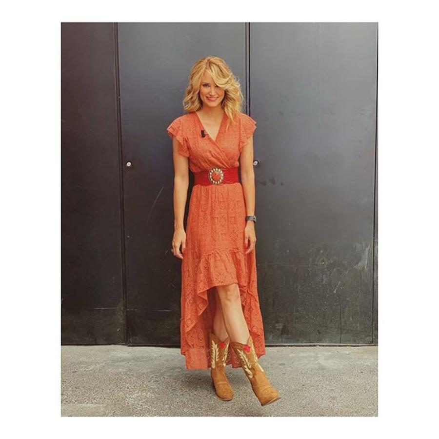 Alba Carrillo apuesta por la estética boho de inspiración folk con este vestido de encaje color coral con falda asimétrica de Llámame Loca. Las botas 'cowboy' son la clave del look.