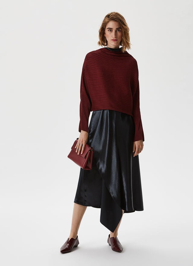 Una falda midi negra de raso fluido como esta de la nueva colección de Adolfo Domínguez, con detalle de godet lateral, es un básico que nunca pasa de moda y es súper fácil de combinar para conseguir un look de invitada perfecto. Precio: 128 euros.