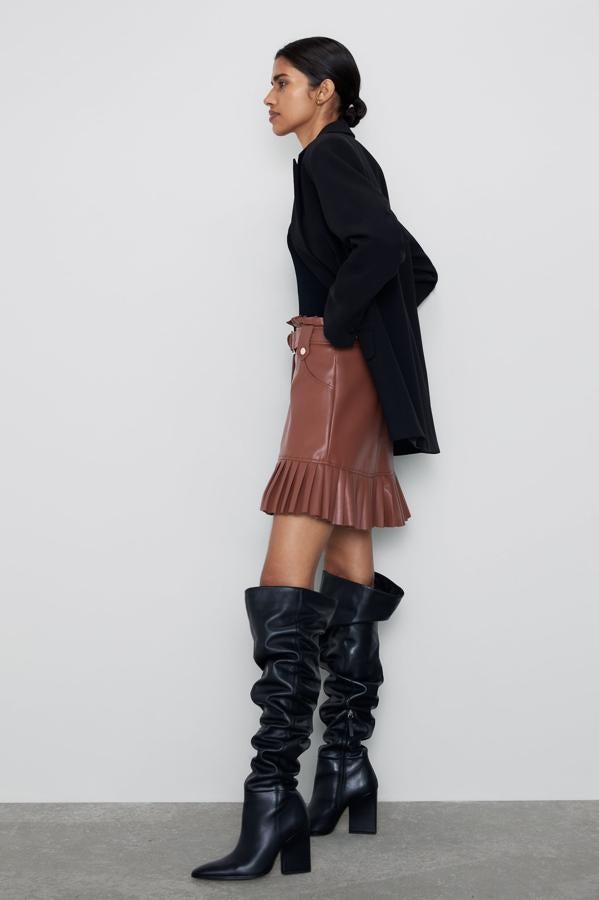 De efecto piel, es recta con el bajo tableado para dar movimiento mientras caminas. Es de Zara y nos ha encantado la combinación con las botas extra altas (25,95 euros).