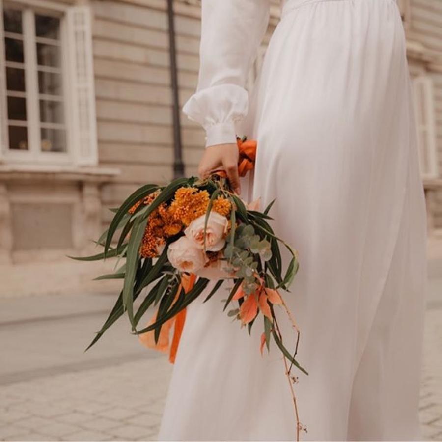 Un ramo de flores adornado con un lazo de seda teñido con tintes naturales como este de Warm&Wild.