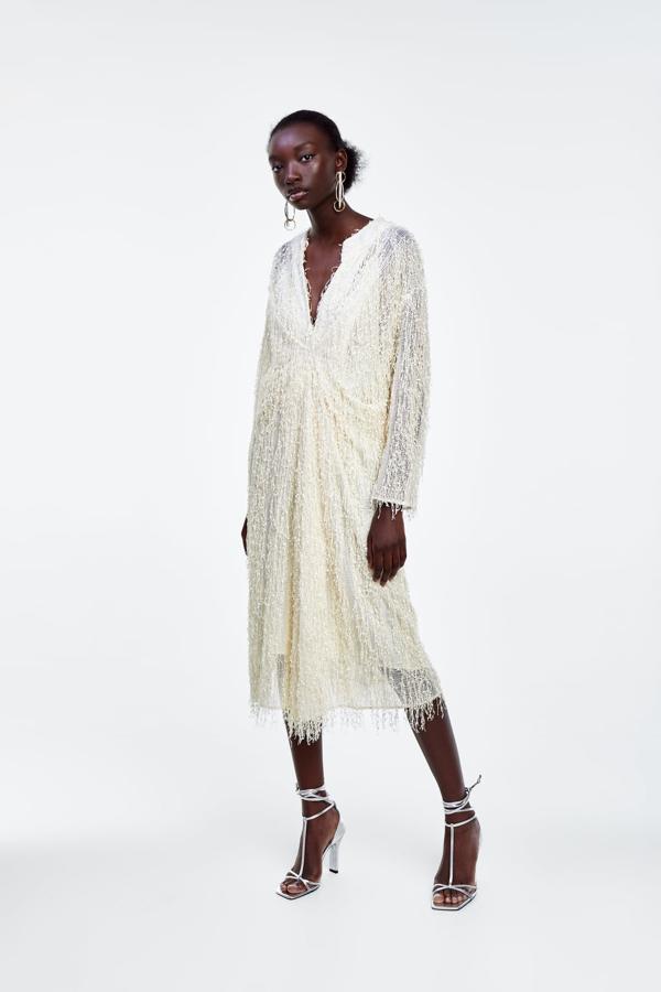 Este es uno de los vestidazos midi de Zara perfecto para un look de invitada. Es un modelo blanco roto de flecos brillantes que cuesta 79,95 euros.