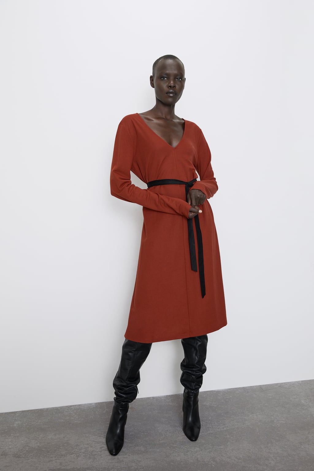 Vestido midi de manga larga en tono caldera de la nueva colección de Zara. Su cinturón tipo lazo resultará de lo más cómodo. (22,95 euros).