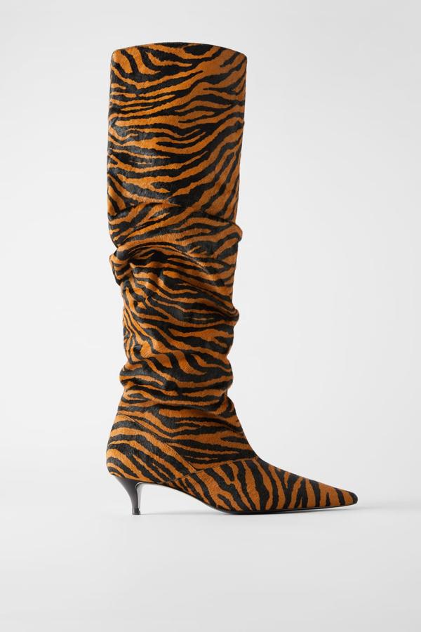 Bota de tacón de piel con estampado de cebra, caña alta ancha arrugada y tacón kitten en contraste de color. Está acabada en punta (Zara, 129 euros).