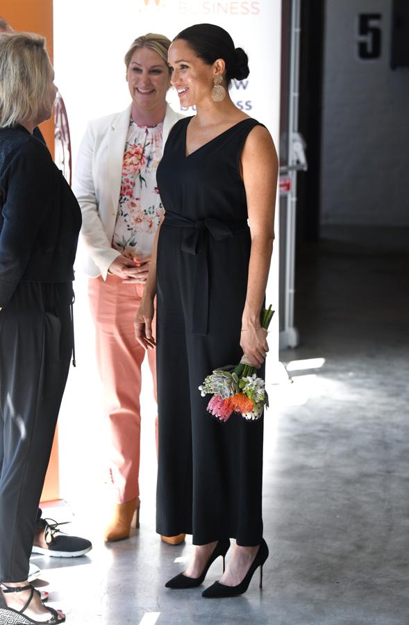 Para su primer acto en solitario en Sudáfrica Meghan Markle apostó por un sencillo mono negro con cinturón de Everlane, un diseño muy versátil y 'low cost' que cuesta poco más de 100 euros.