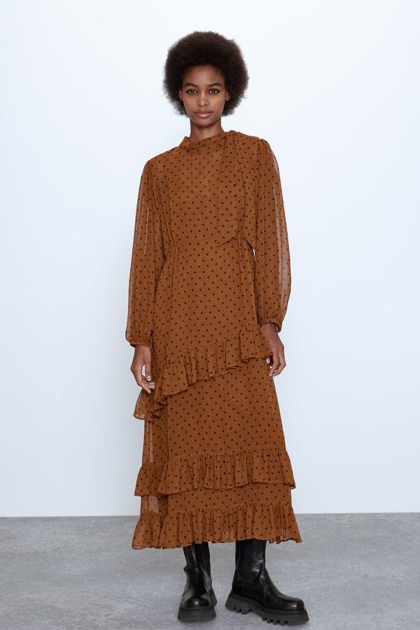 Vestido midi de cuello redondo con lazada y manga larga abullonada, y detalle de pliegues y volantes. Va forrado (Zara, 39,95 euros). Botín de piel color negro, con micro tachas en el contorno de la suela y un tirador con pieza metálica en la parte trasera (Zara, 79,95 euros).