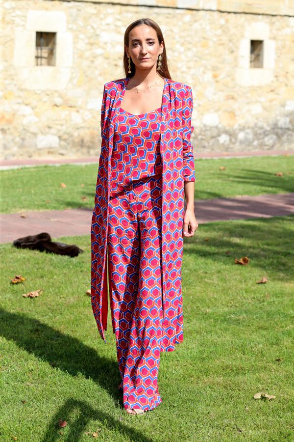 Lucía Pombo eligió un look lleno de color. Se trata de un conjunto a tres piezas de pantalón ancho, top y túnica de media manga y largo midi, con un estamapado geométrico donde domina el fucsia..