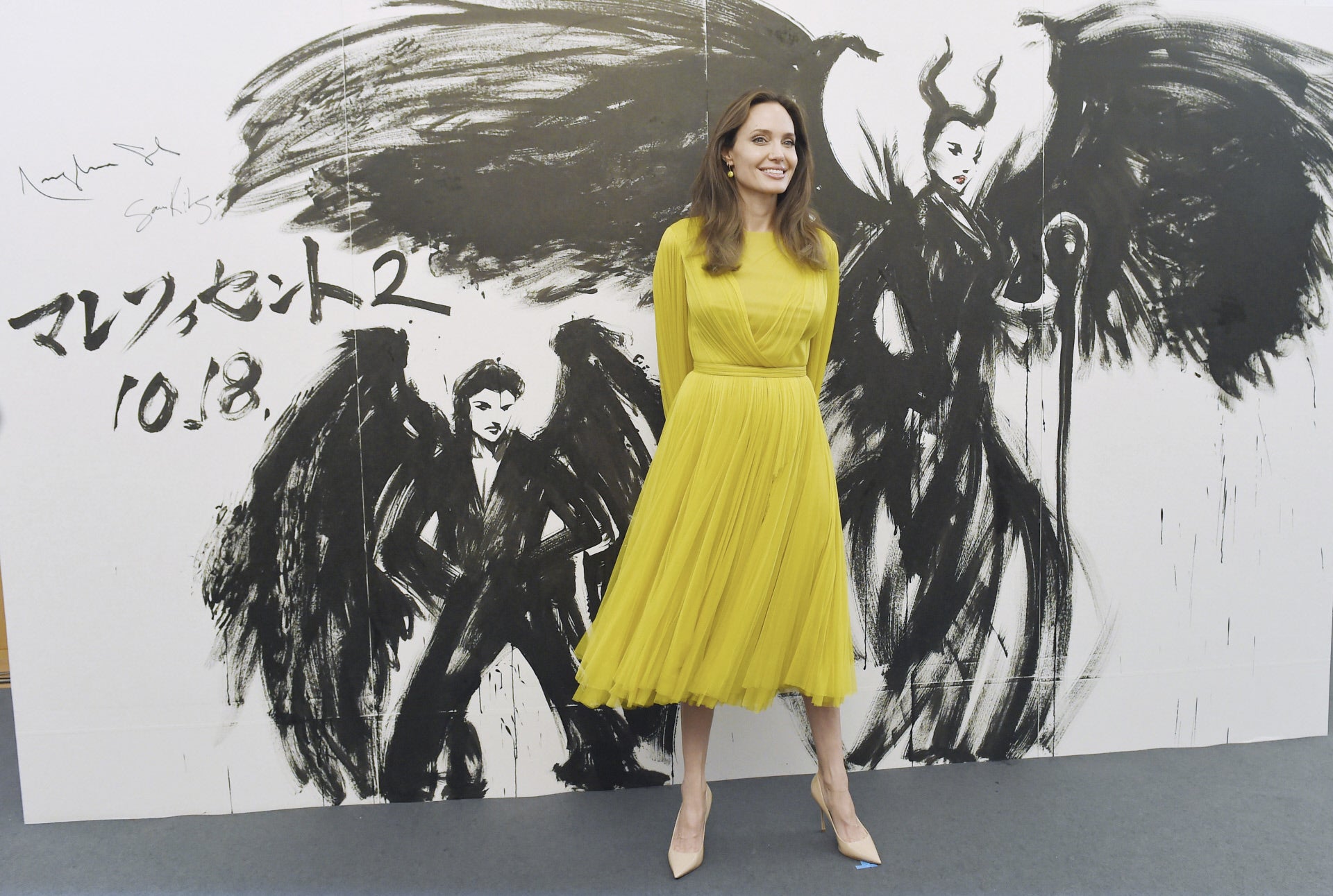 Para el pase de día en Tokio Angelina Jolie eligió un precioso vestido midi en tul amarillo.