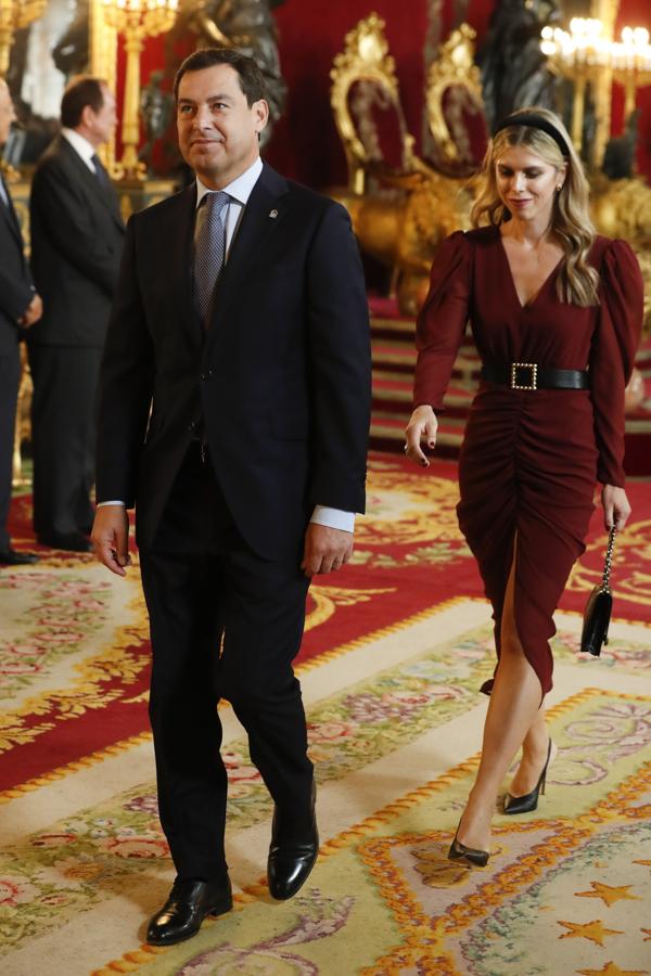 Manuela Villena, pareja del Presidente de la Junta de Andalucía, ha sido una de nuestras favoritas en este besamanos de la Fiesta Nacional gracias a un precioso vestido rojo sangre con mangas en volumen, falda drapeada con abertura y cintura marcada.