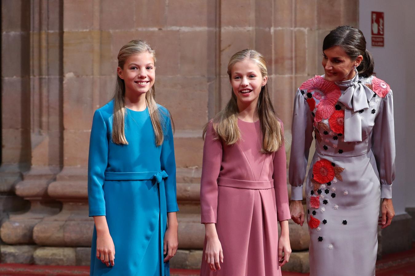 Como ya ocurrió en el desfile del Día de la Hispanidad, la Reina Letizia, que ha estrenado un vestido maravilloso que vamos a copiar en nuestros próximos looks de invitada, ha combinado su look con el de la Princesa Leonor. La semana pasada ambas apostaron por total look en rosa bebé, y esta vez, la Reina ha coincidido con la Infanta Sofía en el azul del fondo, y con Leonor en el rosa del estampado floral.