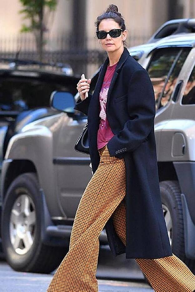 Holmes compensa su look desenfadado con su abrigo negro de solapas.