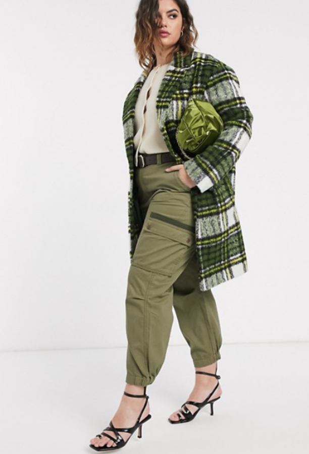 Fantástico estilismo de Asos Design Curve, con abrigo verde con diseño cepillado a cuadros (89,99 euros) y pantalones cargo de corte slim en caqui (35,99 euros).