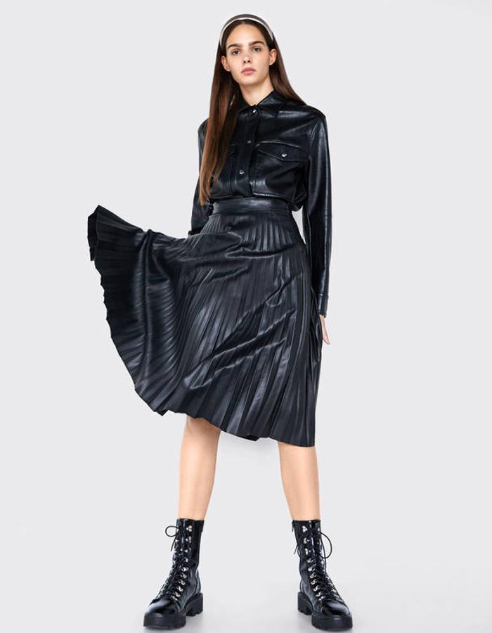 Falda plisada (Bershka, 29,99 euros) y sobrecamisa (Bershka, 39,99 euros), ambos de piel sintética; y botines acordonados con plataforma y suela track (Bershka, 39,99 euros).