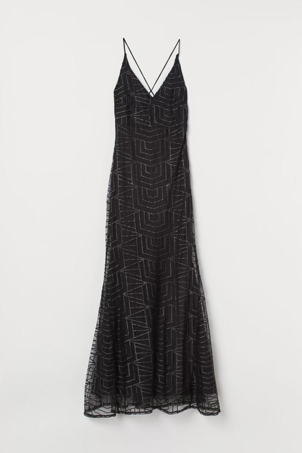 Vestido largo de malla con diseño brillante y bajo con vuelo (59,99 euros). Lleva tirantes espagueti cruzados y anudados en la espalda, cremallera oculta en un lateral y costura en la cintura. El escote de pico va delante y detrás, aunque más pronunciado en la espalda. El forro es de satén.