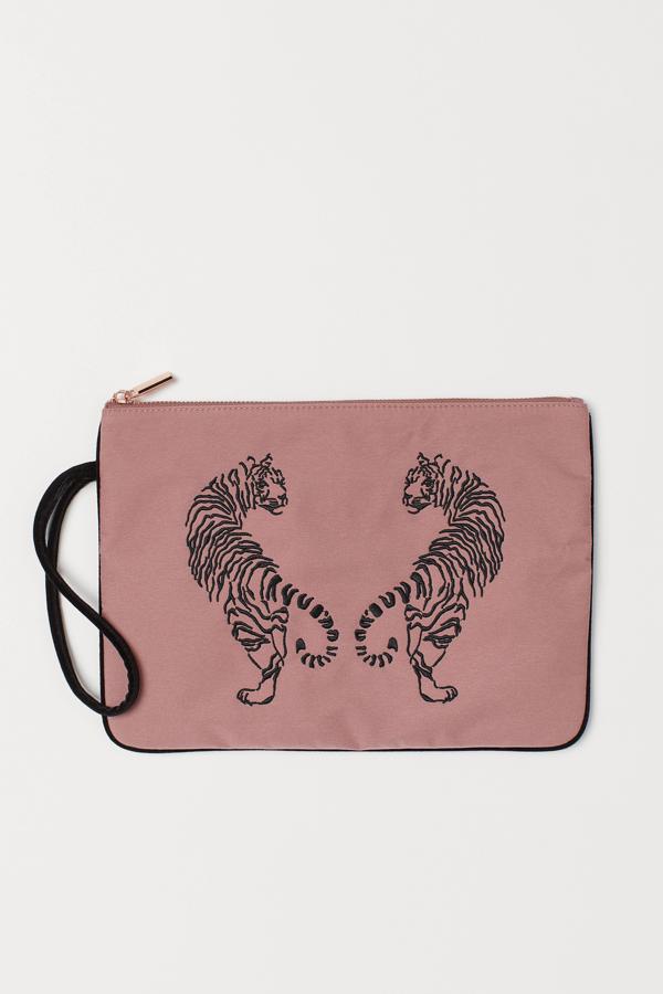Uno de las más grandes de esta selección es esta cartera de mano de H&M en color rosa vintage. Con detalles de terciopelo y unos tigres bordados en la parte delantera, es uno de los más baratos de la selección, con un precio de 9,99 euros.
