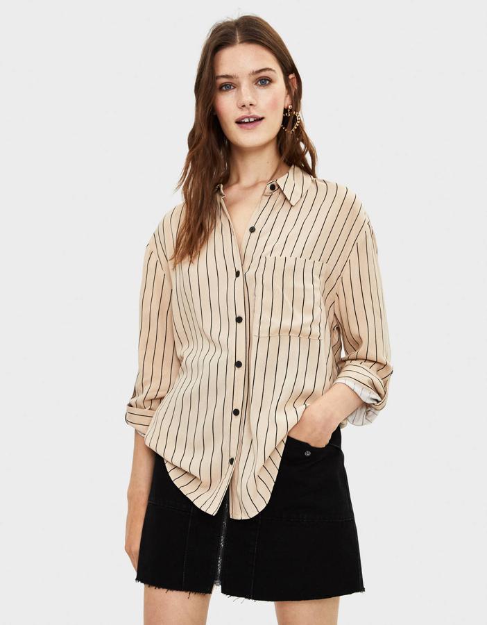 Beige, con rayas negras y botones en el mismo color. Está disponible en todas las tallas menos la L, y es la camisa ideal si el traje negro es un habitual de tus estilismos.