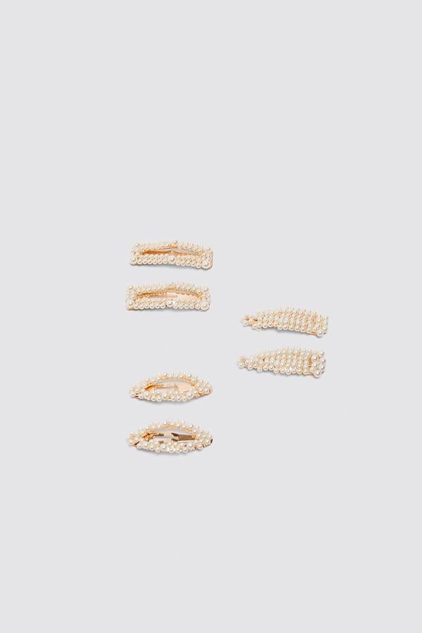Pinzas en tonos dorados combinadas con aplicación de perlas en tres versiones, tradicional, rectangular y redondeada. Están en Zara por 12,95 euros y tienen formato mini.