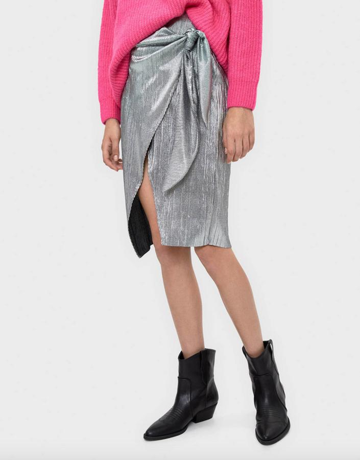 Es de Bershka y cuesta 22,99 euros. Tiene una abertura terminada en nudo con lazo que crea un efecto muy innovador para una de las faldas midi metalizadas de esta selección.
